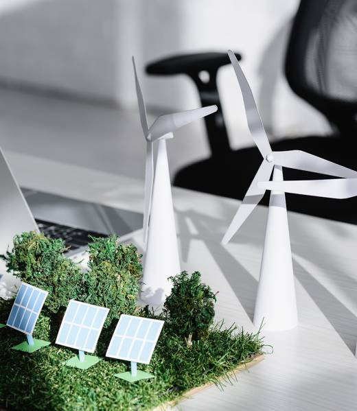 chair near table with laptop, trees, windmills, solar panels models on grass in office
